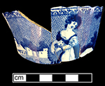 Pearlware London shaped handled cup printed underglaze in medium blue with pastoral/genre scene of girl and sheep.  Field dots form background.  Continuous repeating floral interior rim.  No known pattern name or maker. One of a set of two identical cups from this assemblage. Example of similar complete image on right from a private collector.